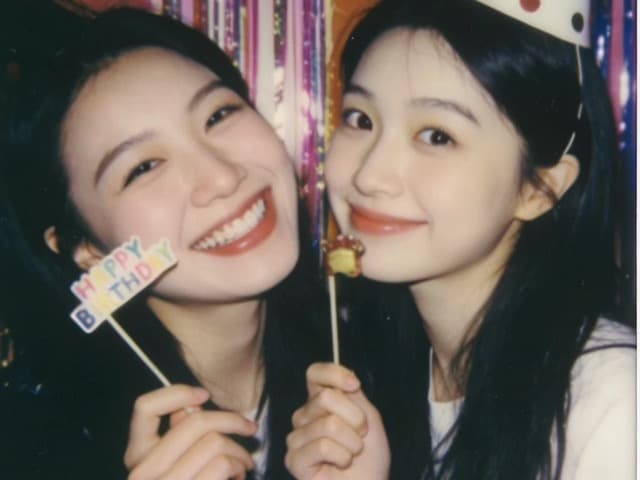 Two friends with party hats and a birthday prop
