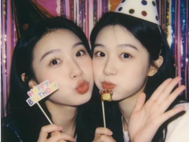 The same two friends, one holding the sign higher