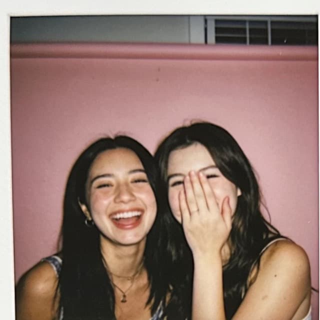 Two friends laughing, one with a hand over her face